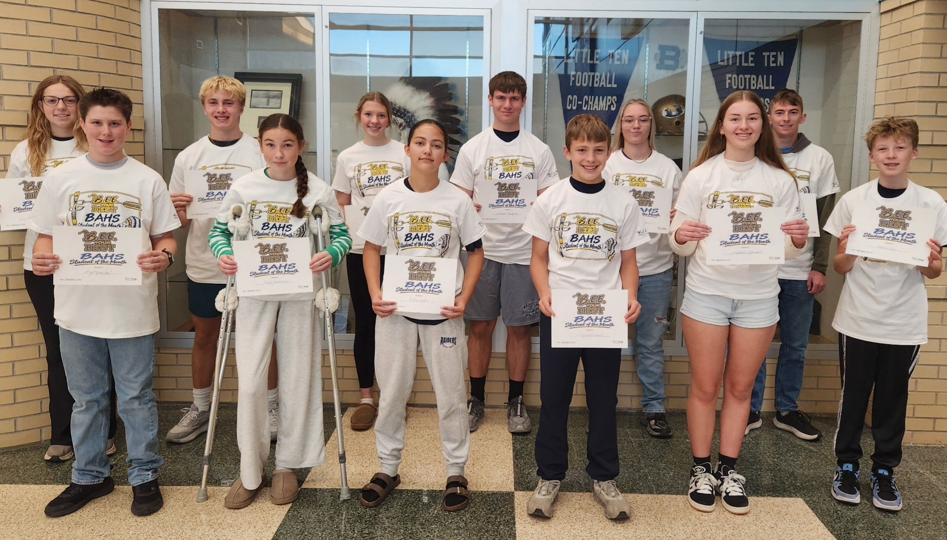 12 students pose for a photo while holding BAHS Student of the Month signs.